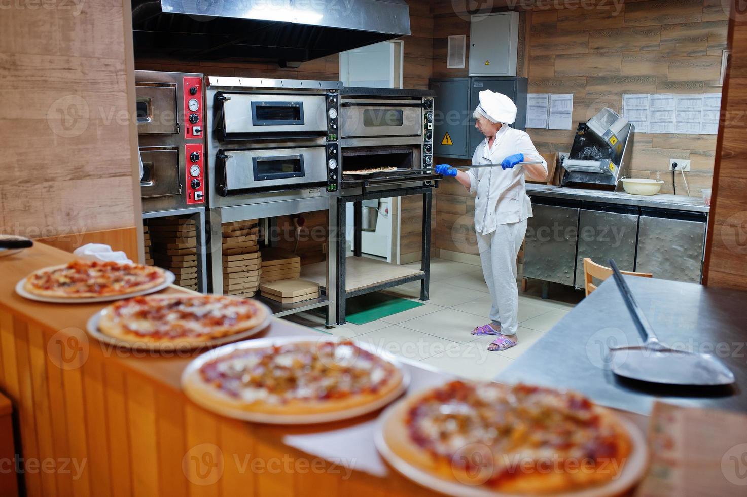 Female chef preparing pizza in restaurant kitchen. photo