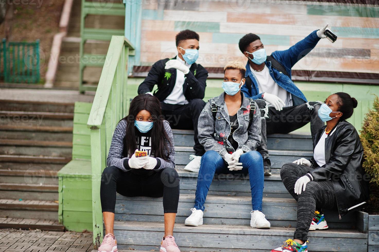 Group of african teenagers friends at park wearing medical masks protect from infections and diseases coronavirus virus quarantine. photo
