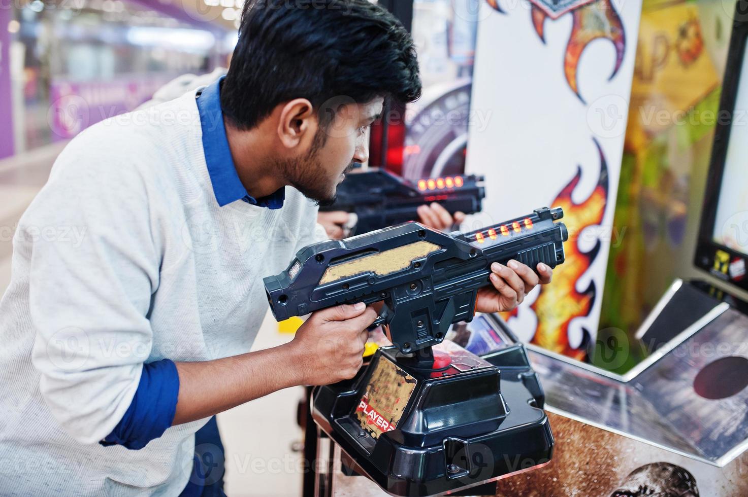 Two asian guys compete on shooter simulator game arcade machine. photo