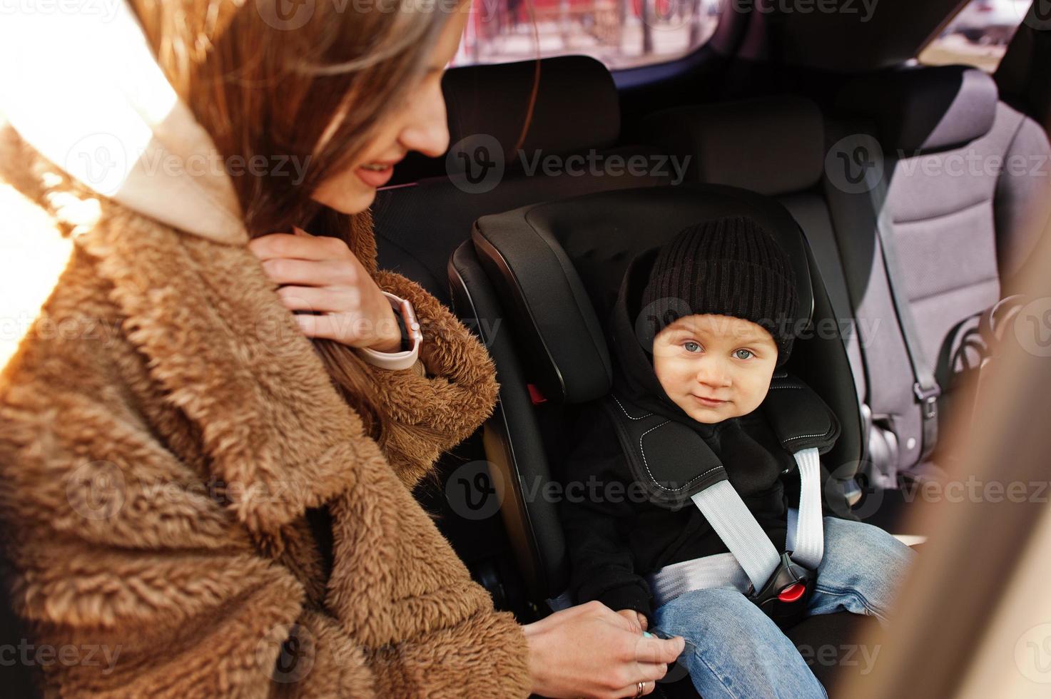 Young mother and child in car. Baby seat on chair. Safety driving concept. photo