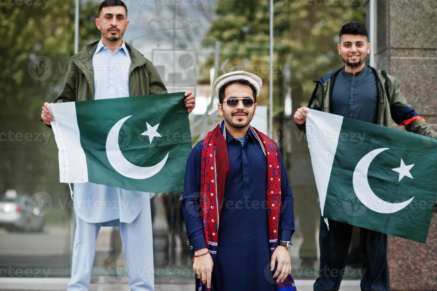 grupo de hombres paquistaníes vestidos con ropa tradicional salwar kameez o kurta con banderas de pakistán. foto