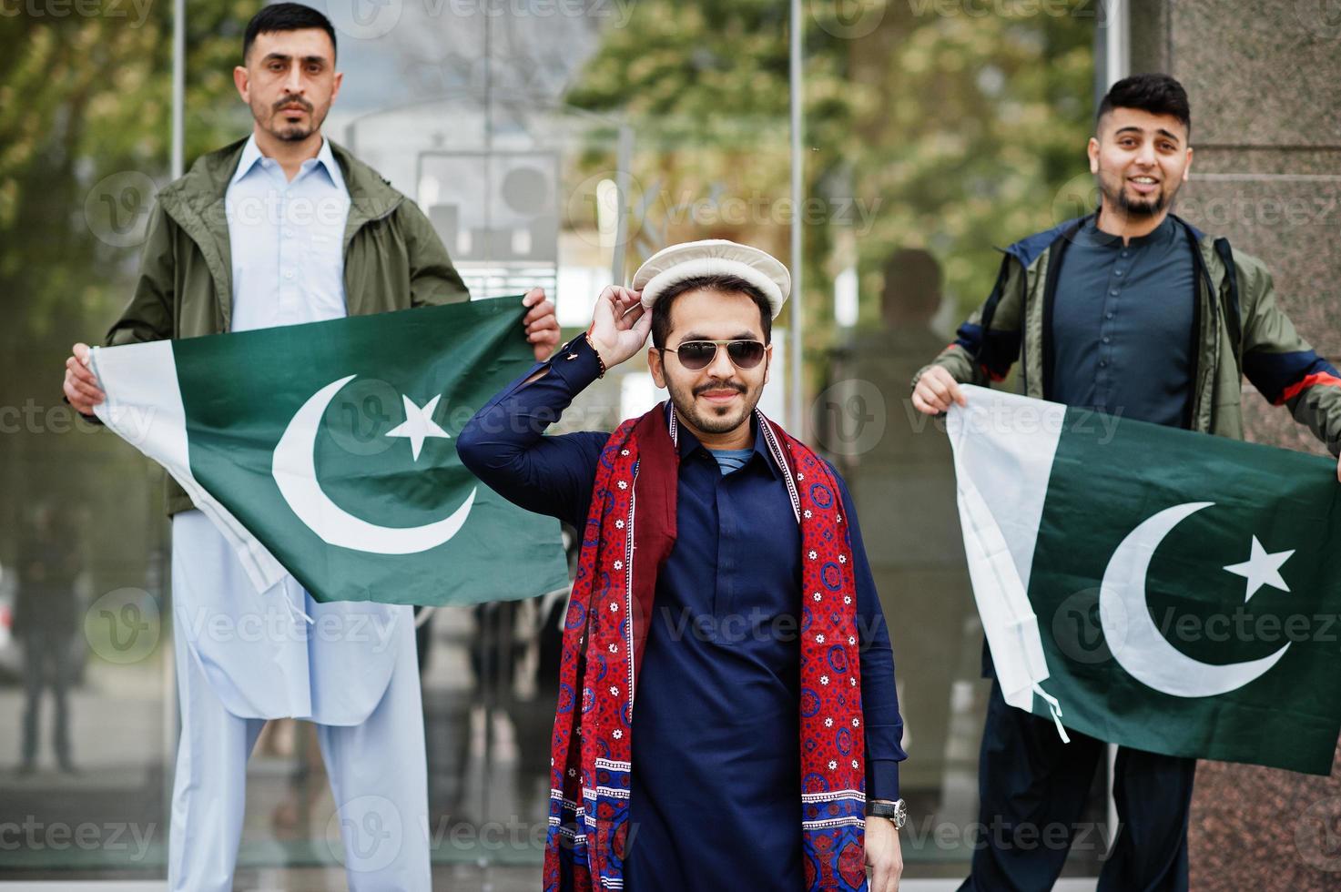 grupo de hombres paquistaníes vestidos con ropa tradicional salwar kameez o kurta con banderas de pakistán. foto