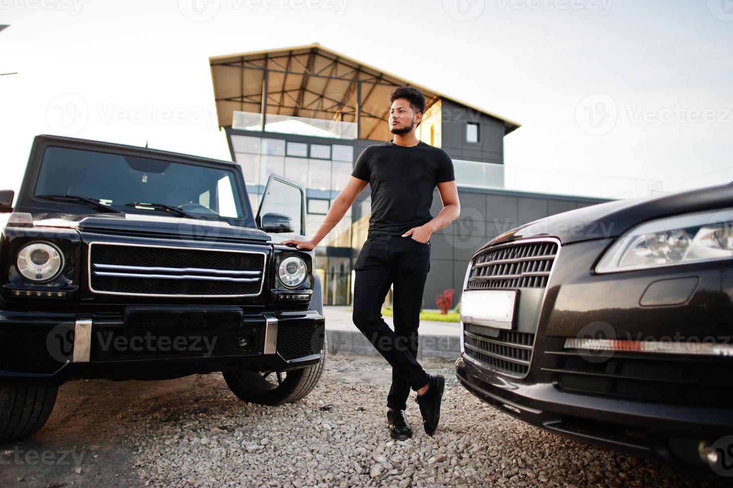 Asian man wear on all black posed near suv car. photo