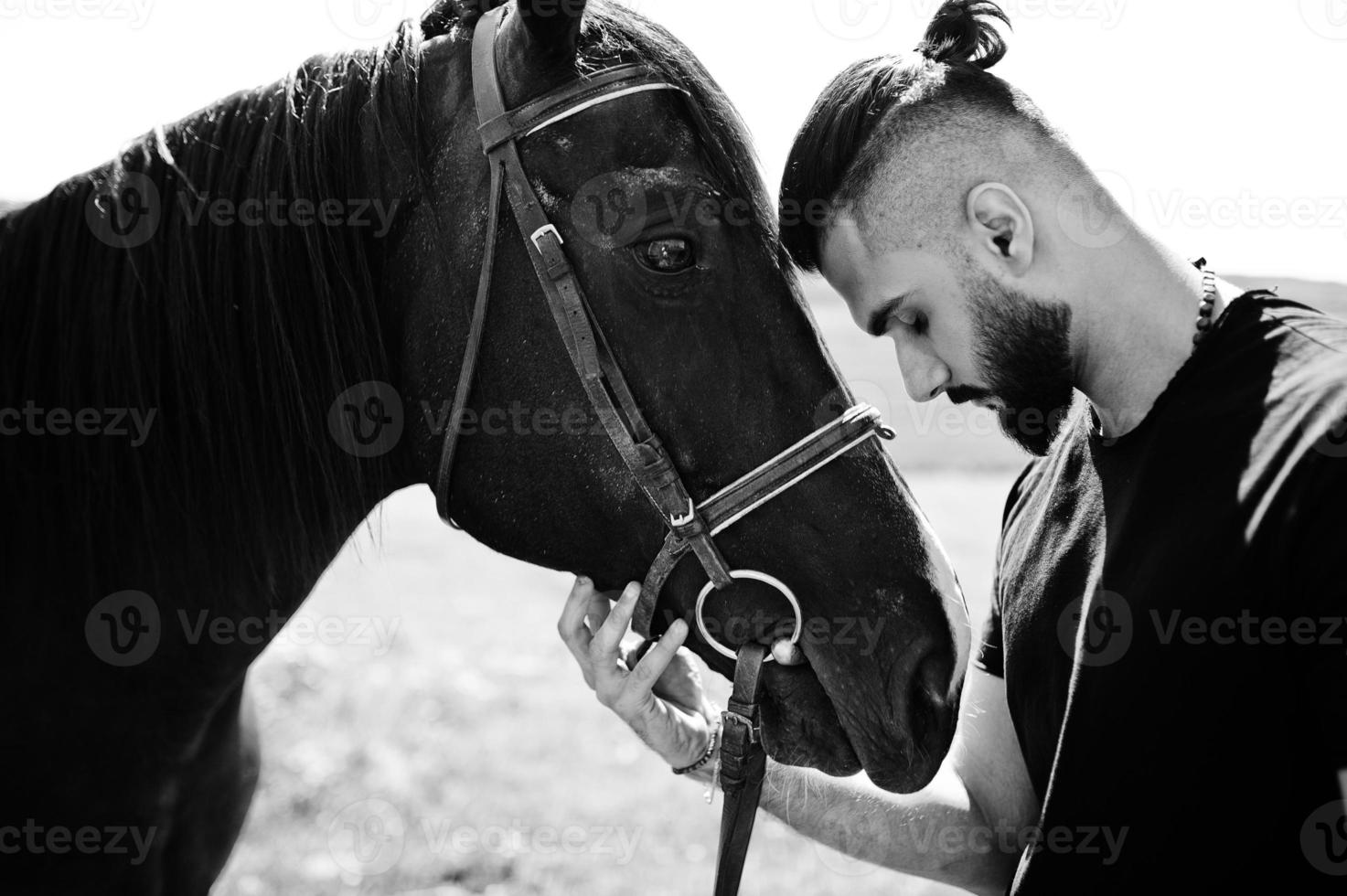 Arab tall beard man wear in black with arabian horse. photo