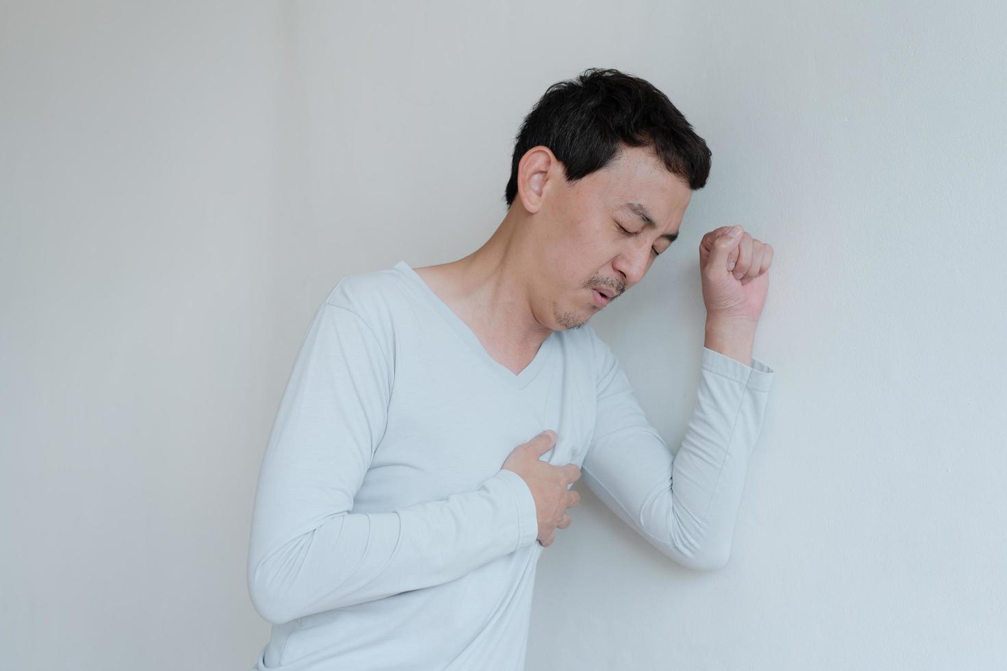 un hombre que toca su corazón, con un punto culminante rojo de ataque al corazón y otros concepto de enfermedad cardíaca, síntoma de ataque al corazón foto