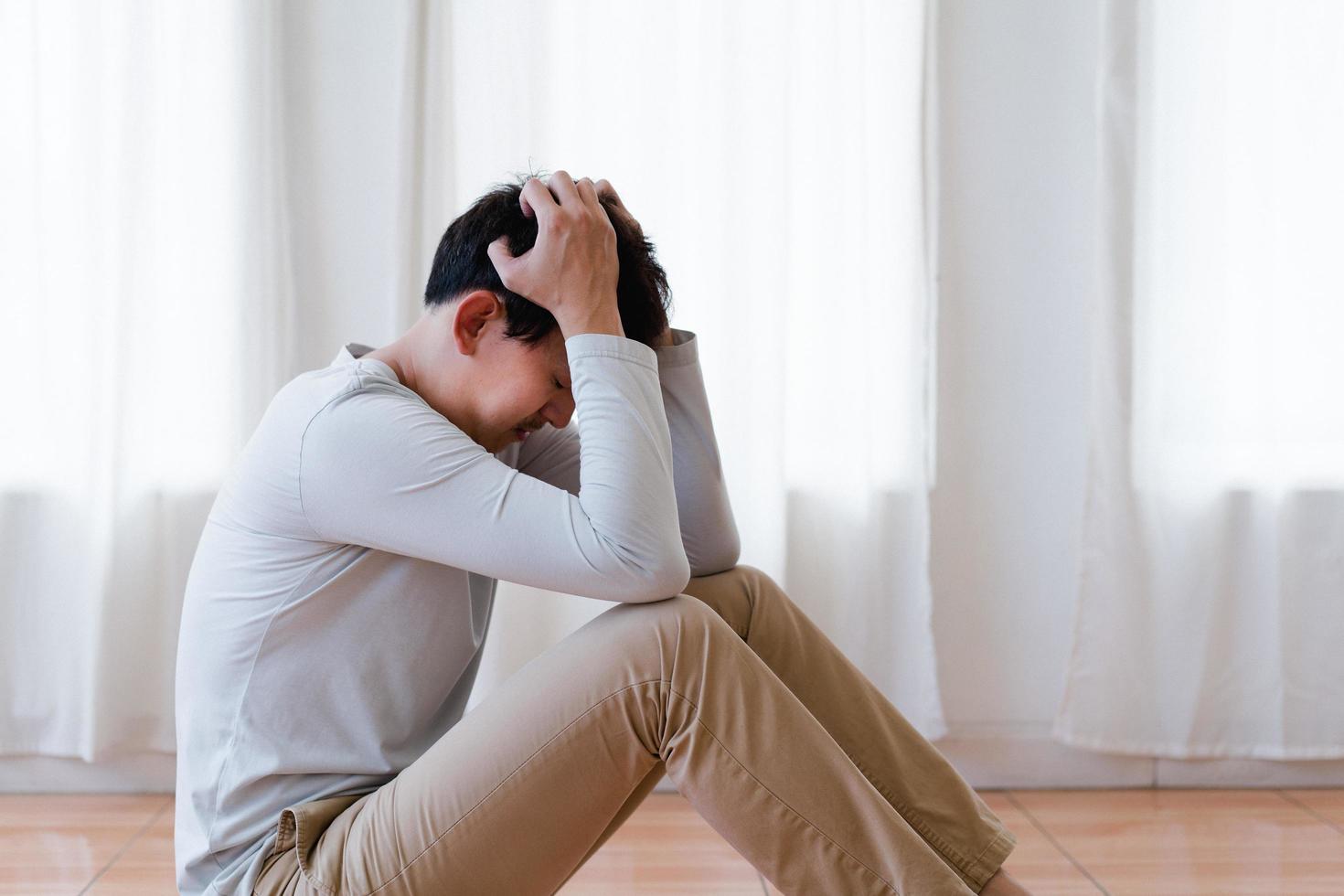Depressed asian young man covering face by hands, crying alone at home, upset man sitting , feeling unhappy after quarrel or breakup, despair and lonely and panic , psychological problem concept photo