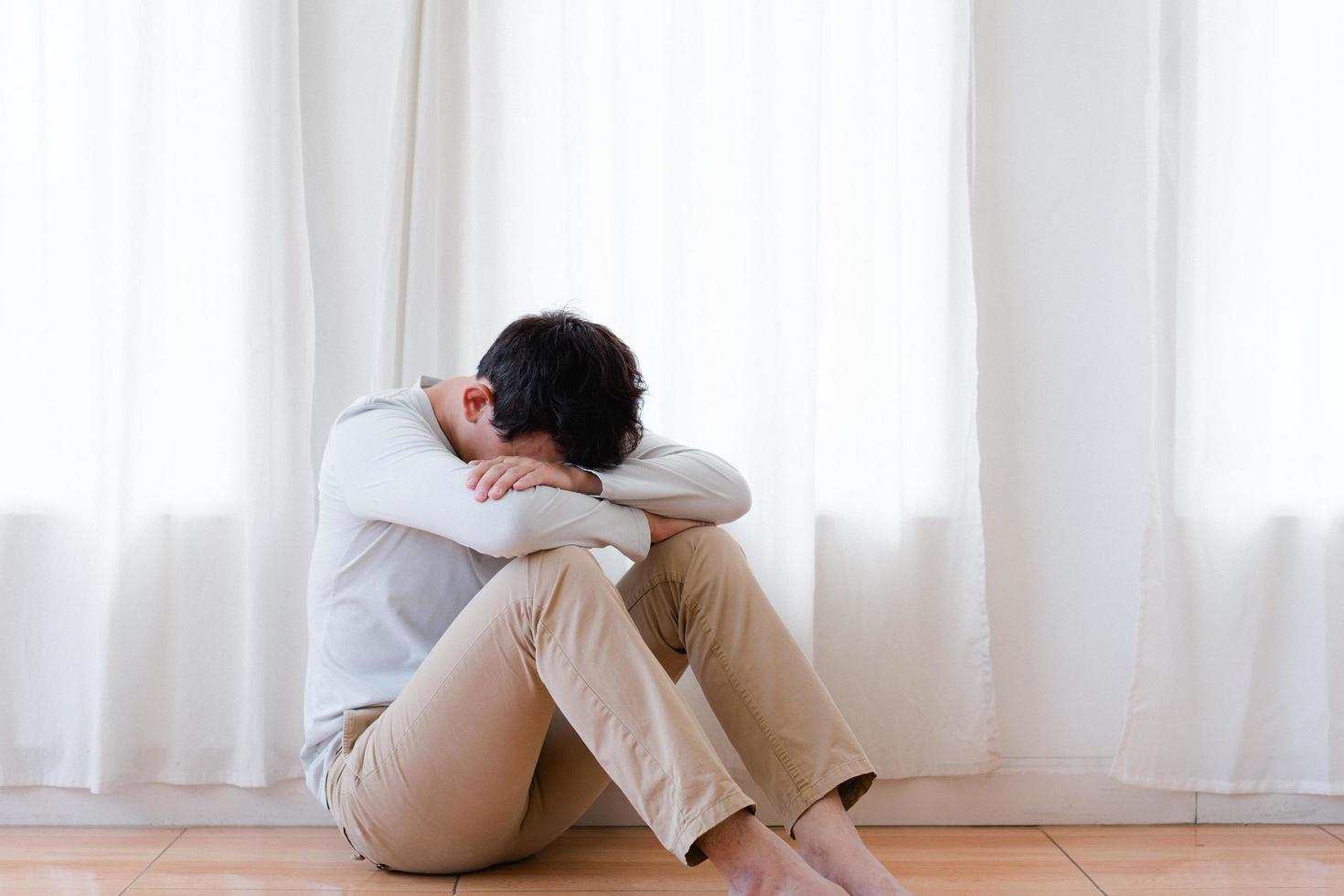 Depressed asian young man covering face by hands, crying alone at home, upset man sitting , feeling unhappy after quarrel or breakup, despair and lonely and panic , psychological problem concept photo