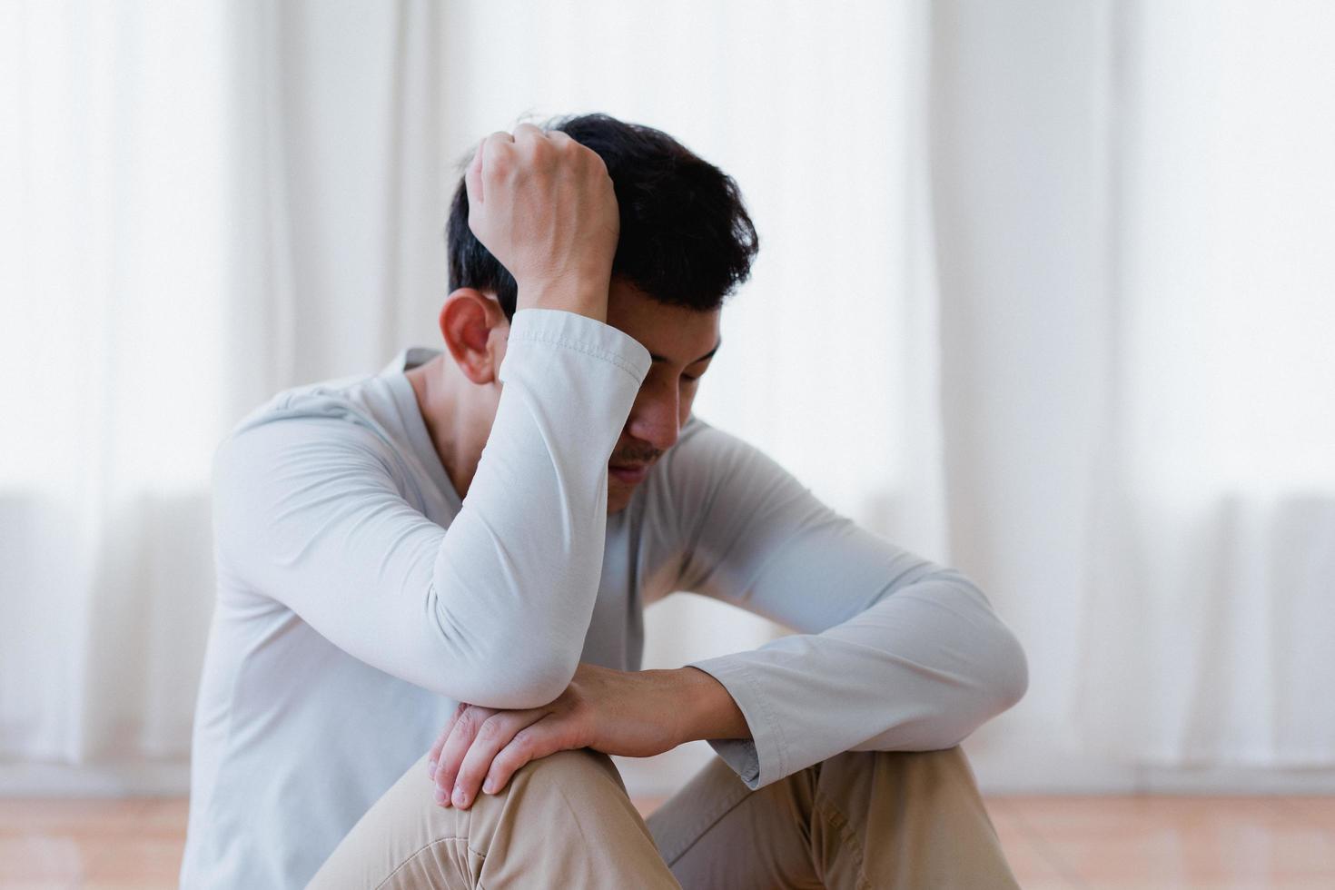Depressed asian young man covering face by hands, crying alone at home, upset man sitting , feeling unhappy after quarrel or breakup, despair and lonely and panic , psychological problem concept photo
