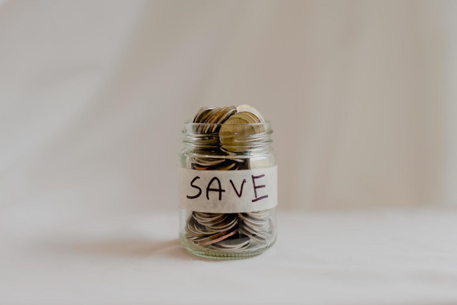 asian woman hand is putting a coin in a glass bottle on wooden table, Investment business, retirement, finance and saving money for future concept. photo