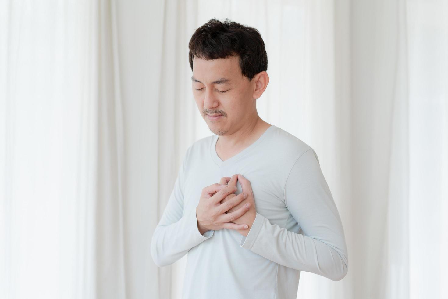 un hombre que toca su corazón, con un punto culminante rojo de ataque al corazón y otros concepto de enfermedad cardíaca, síntoma de ataque al corazón foto