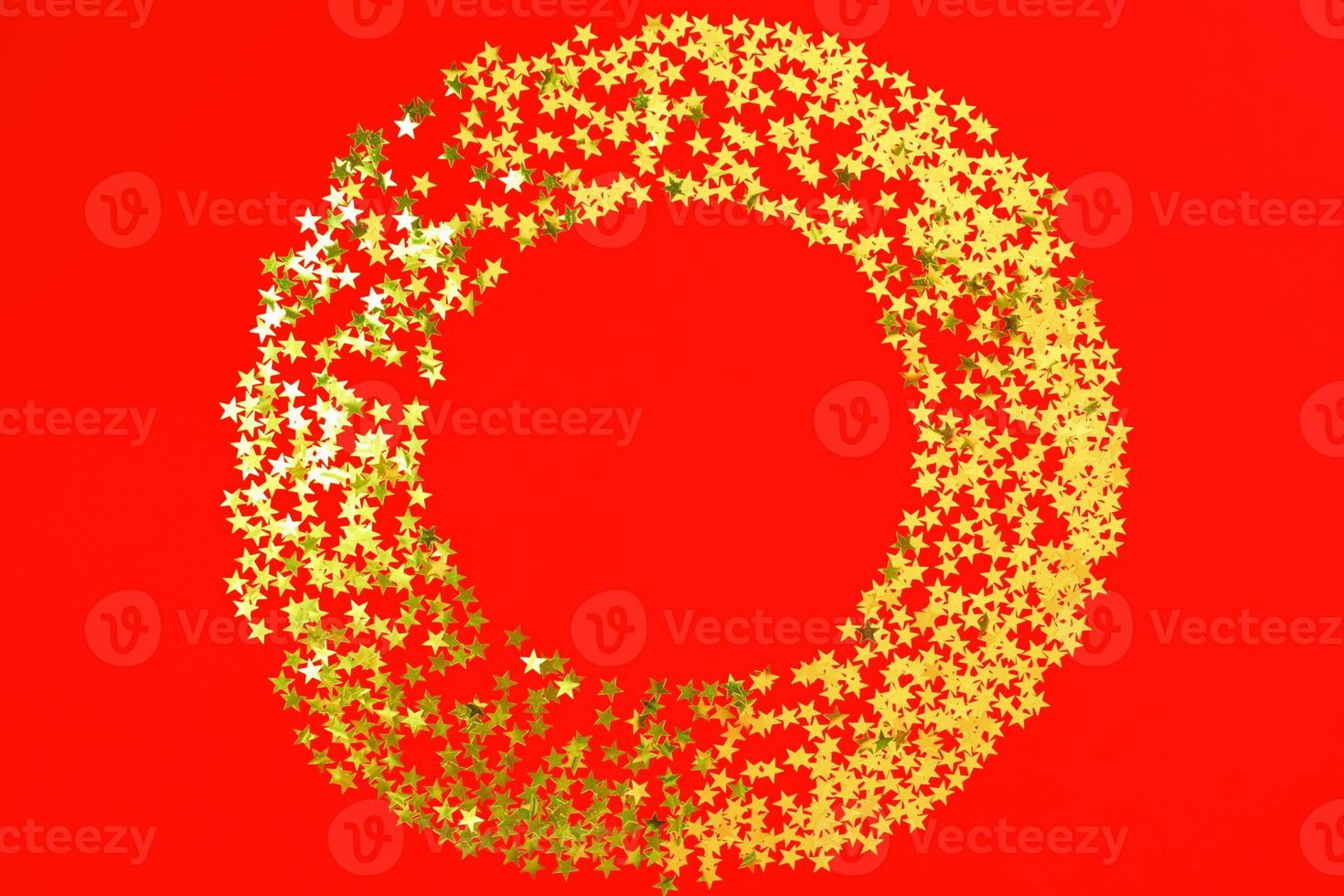 Red backdrop with glitter and golden stars confetti in circle. Festive holiday bright background photo