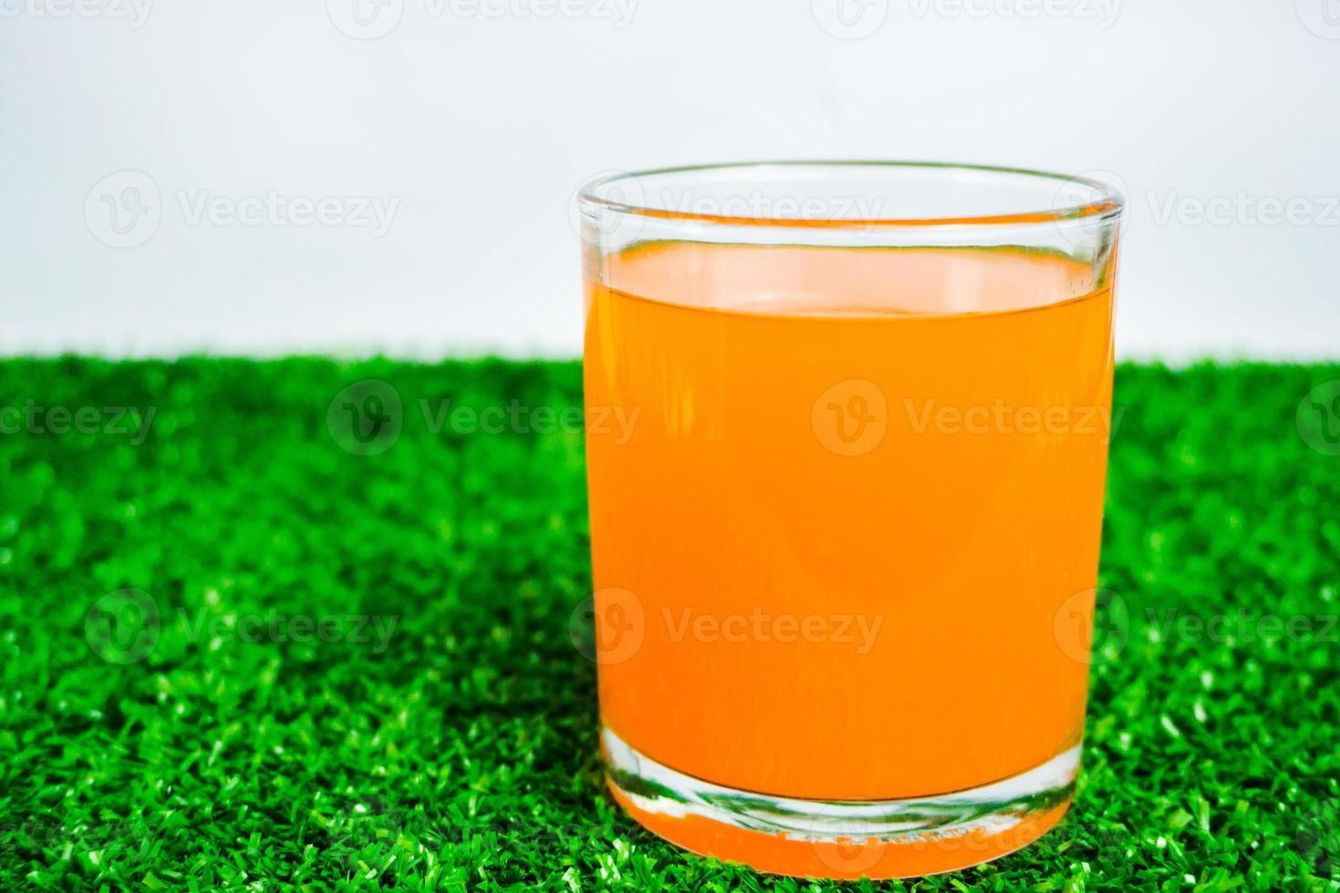 glass of orange juice on a green background photo