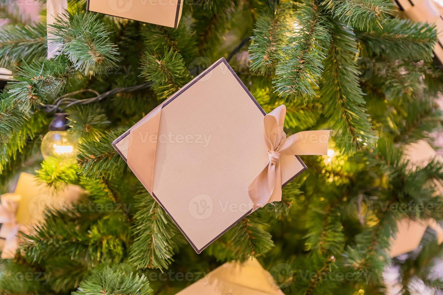 Christmas and New Year holidays background. Christmas tree with garland and giftbox with a bow photo