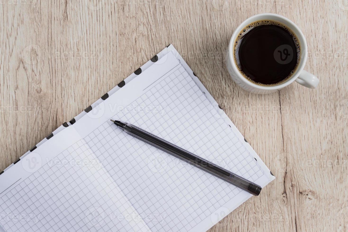 Business and office concept - open blank notebook, pen and cup of black coffee on wooden table. top view. photo
