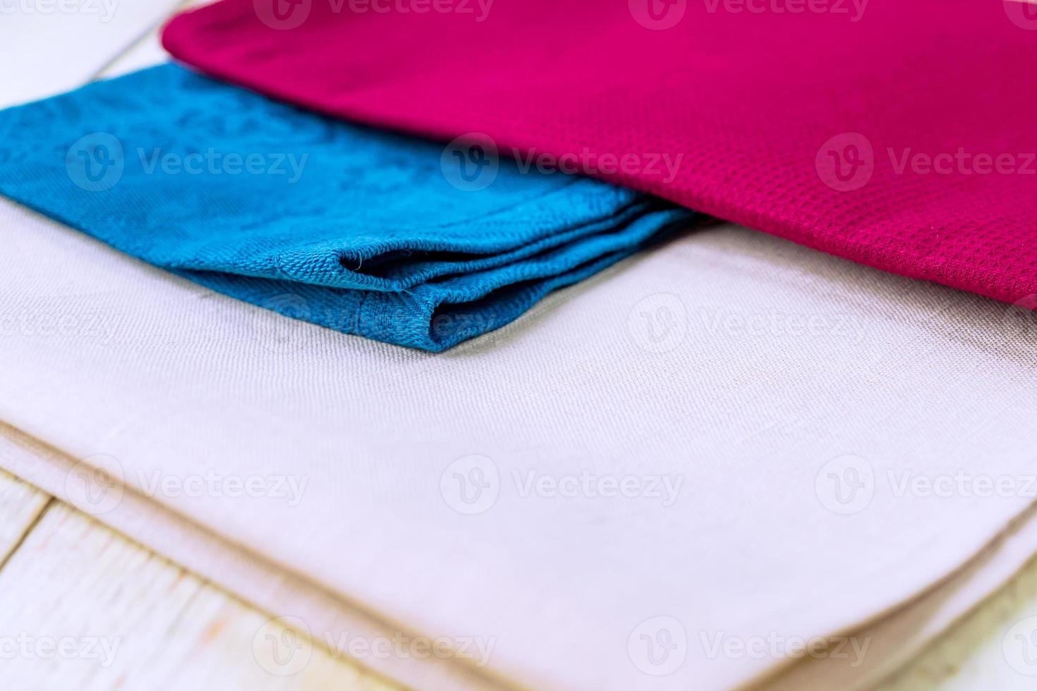 close up of cloth napkins of beige, blue and burgundy colors on rustic white wooden table. Shallow depth of field. photo