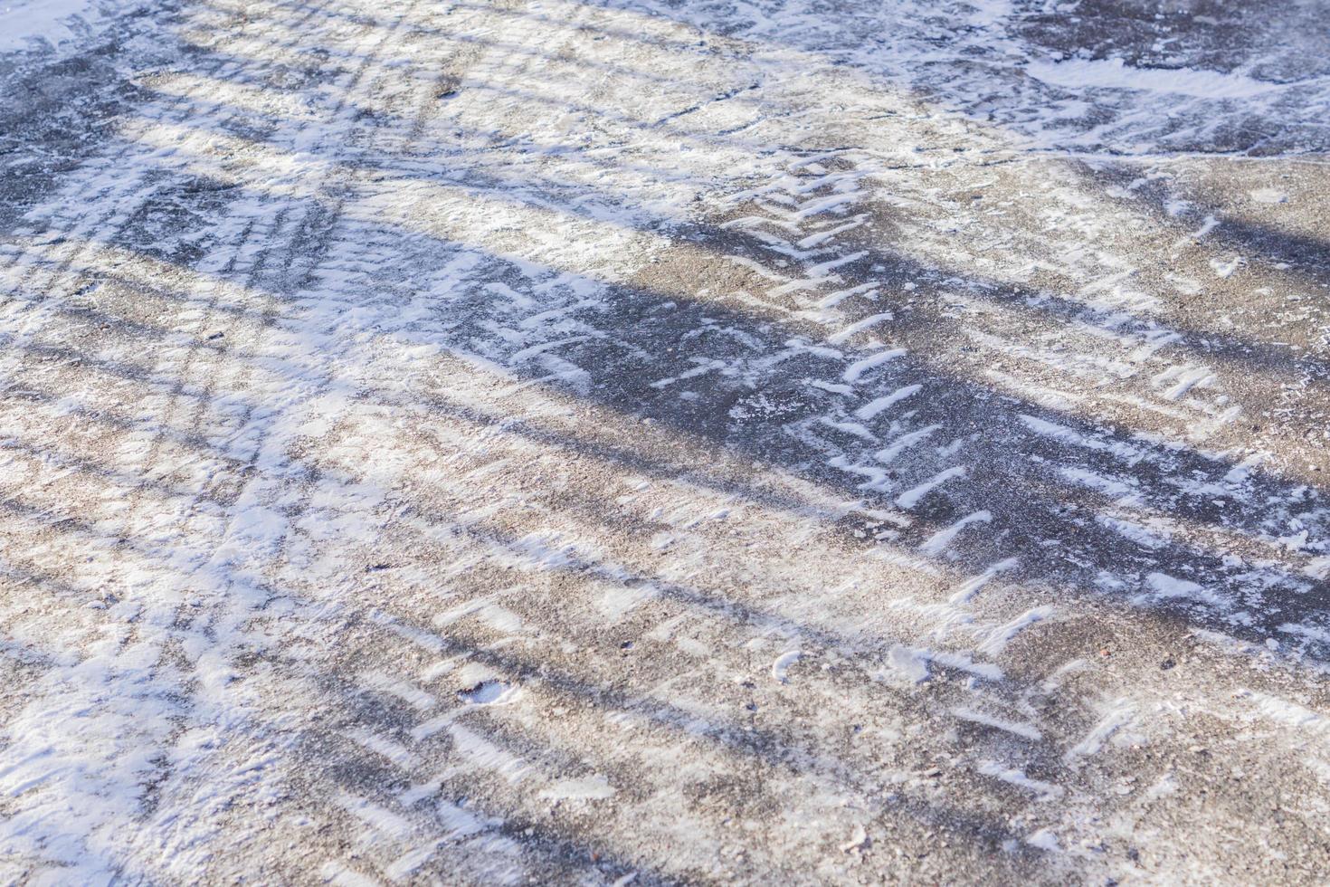 huellas de ruedas en la carretera de invierno cubiertas de nieve en un día soleado foto