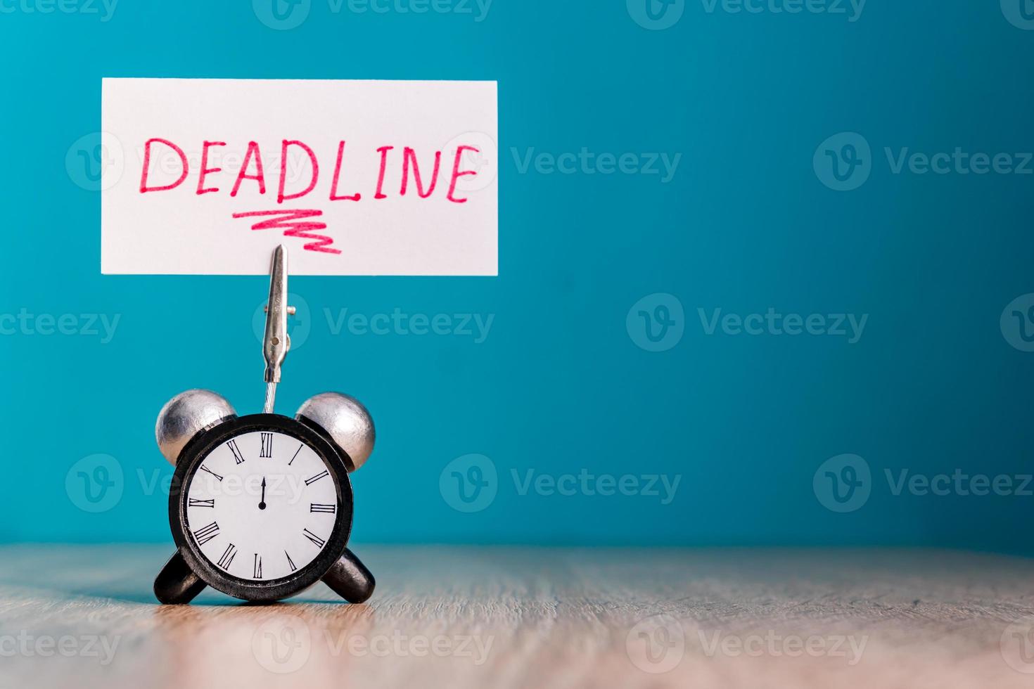 Alarm clock and banner with handwritten word deadline on wooden table. Time management concept. photo