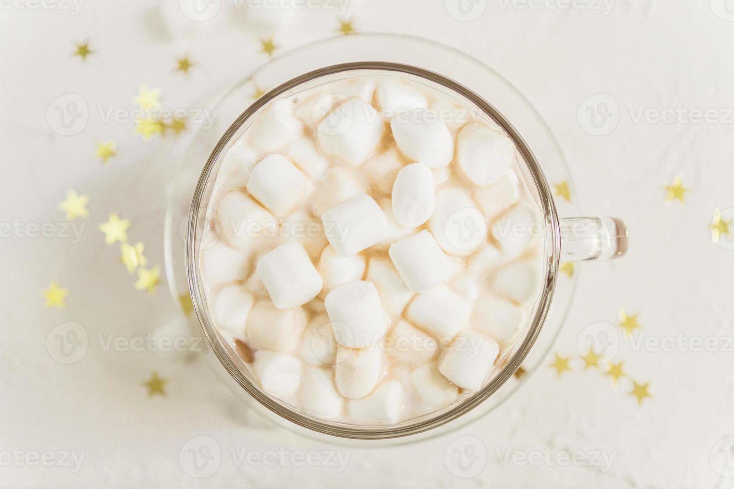 top view of cup of hot delicious cocoa drink with marshmallows on gold stars background photo