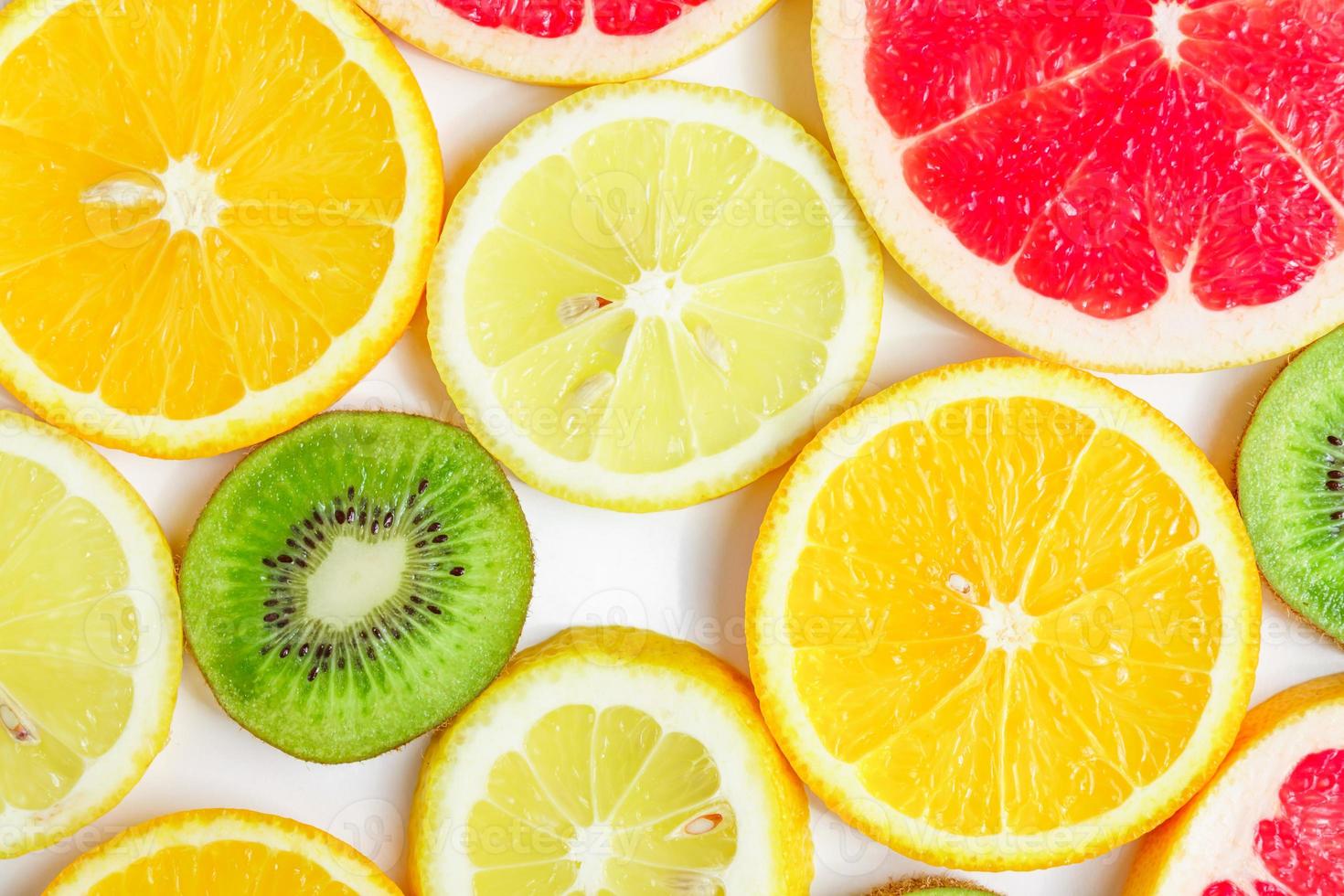 rodajas de cítricos - kiwi, naranjas y pomelos sobre fondo blanco. telón de fondo de frutas foto