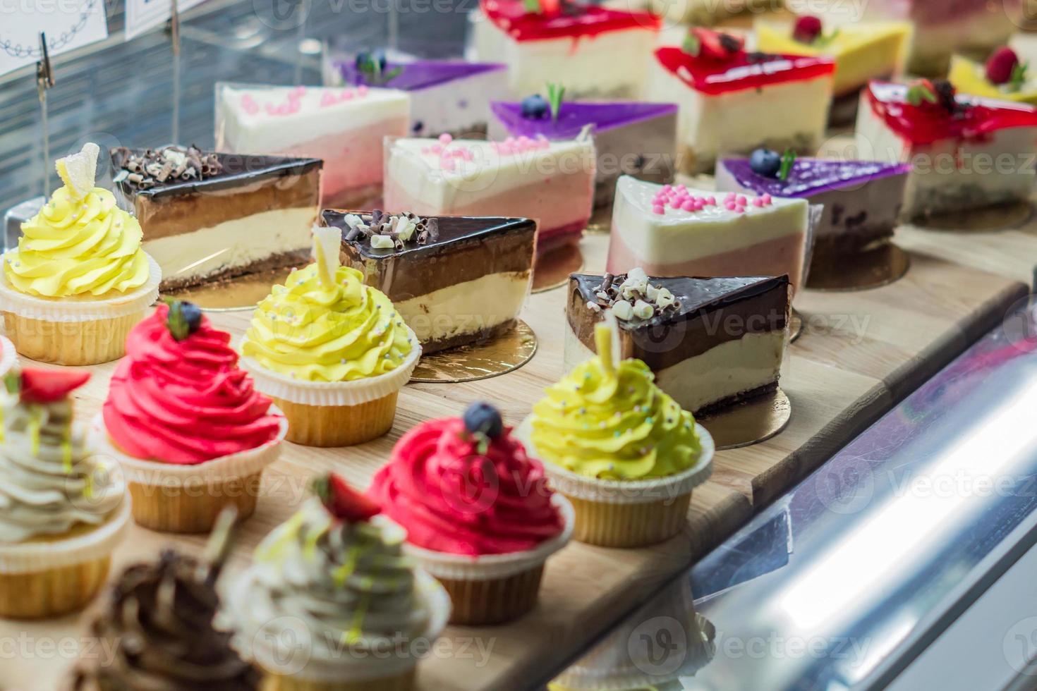 Pastry shop display window with variety of cupcakes and cheesecakes, selective focus photo