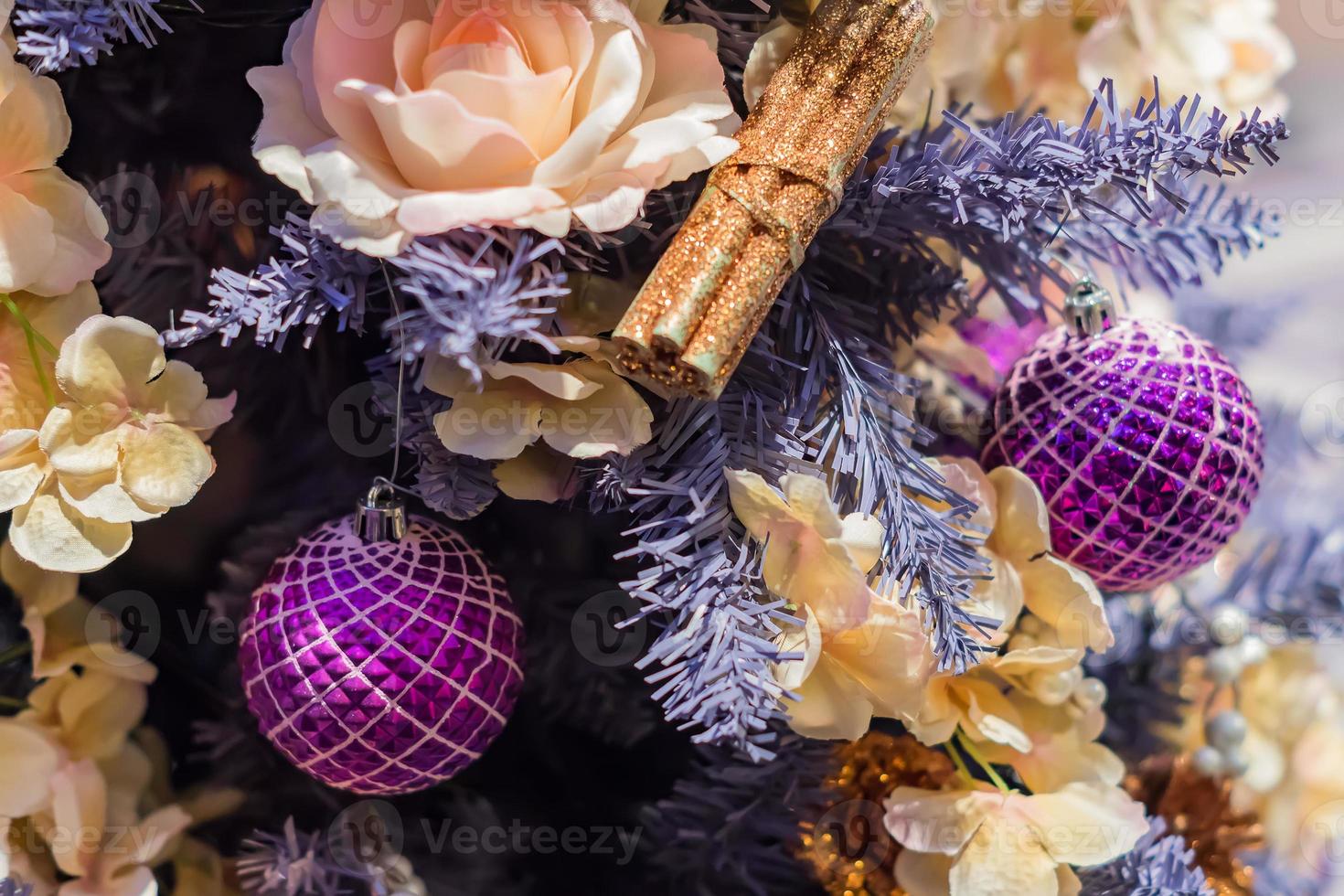 close up of christmas tree decorated with artificial cinnamon sticks and purple balls . New year background photo