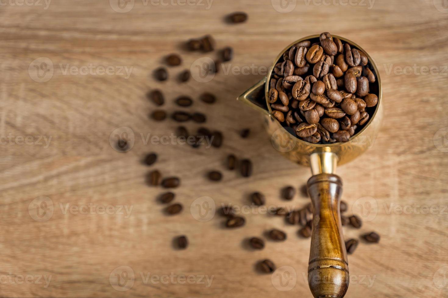 Top view of fresh roasted coffe beans in  cezve traditional turkish coffee pot on wooden table. Selective focus photo