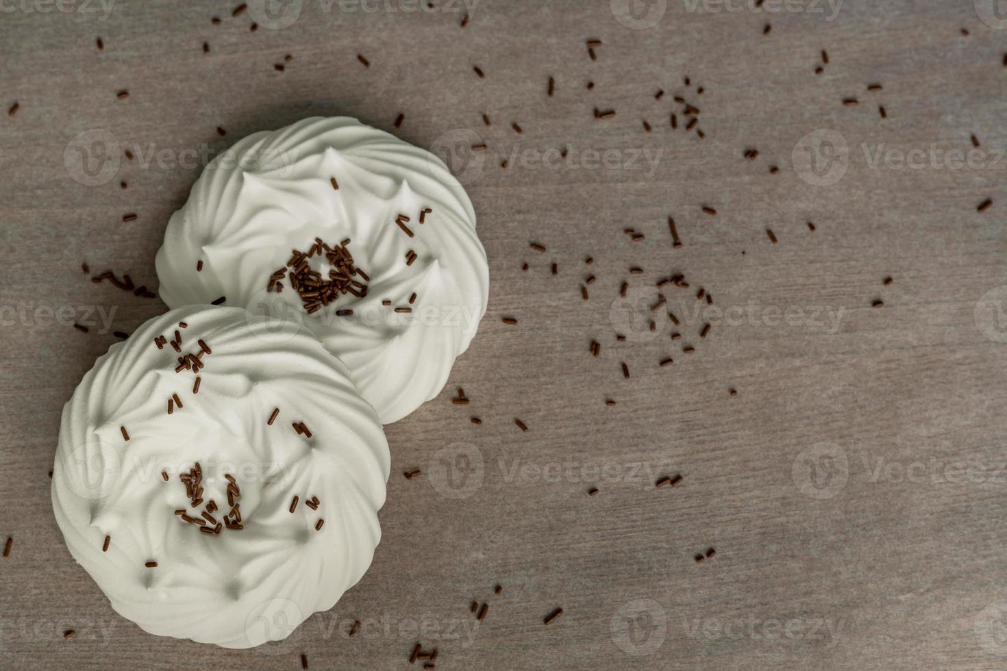 top view of homemade white air meringues and confectionery decorations on  on parchment paper. photo