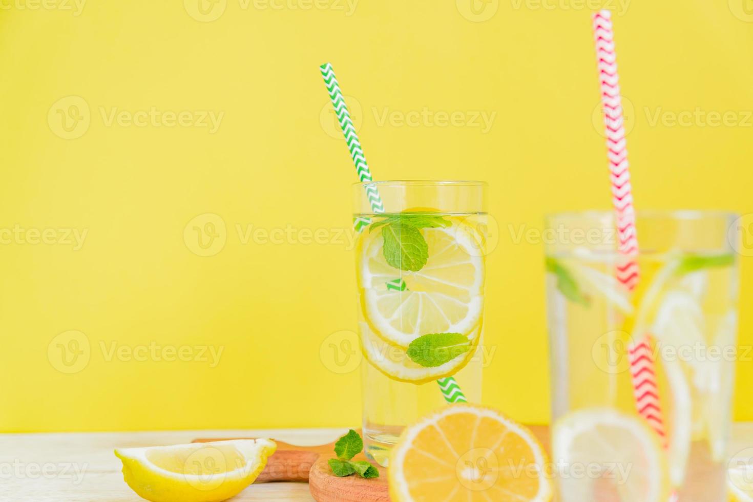 Homemade lemonade with lemon and mint on colored yellow background. Summer cold drink cocktail. Copyspace photo