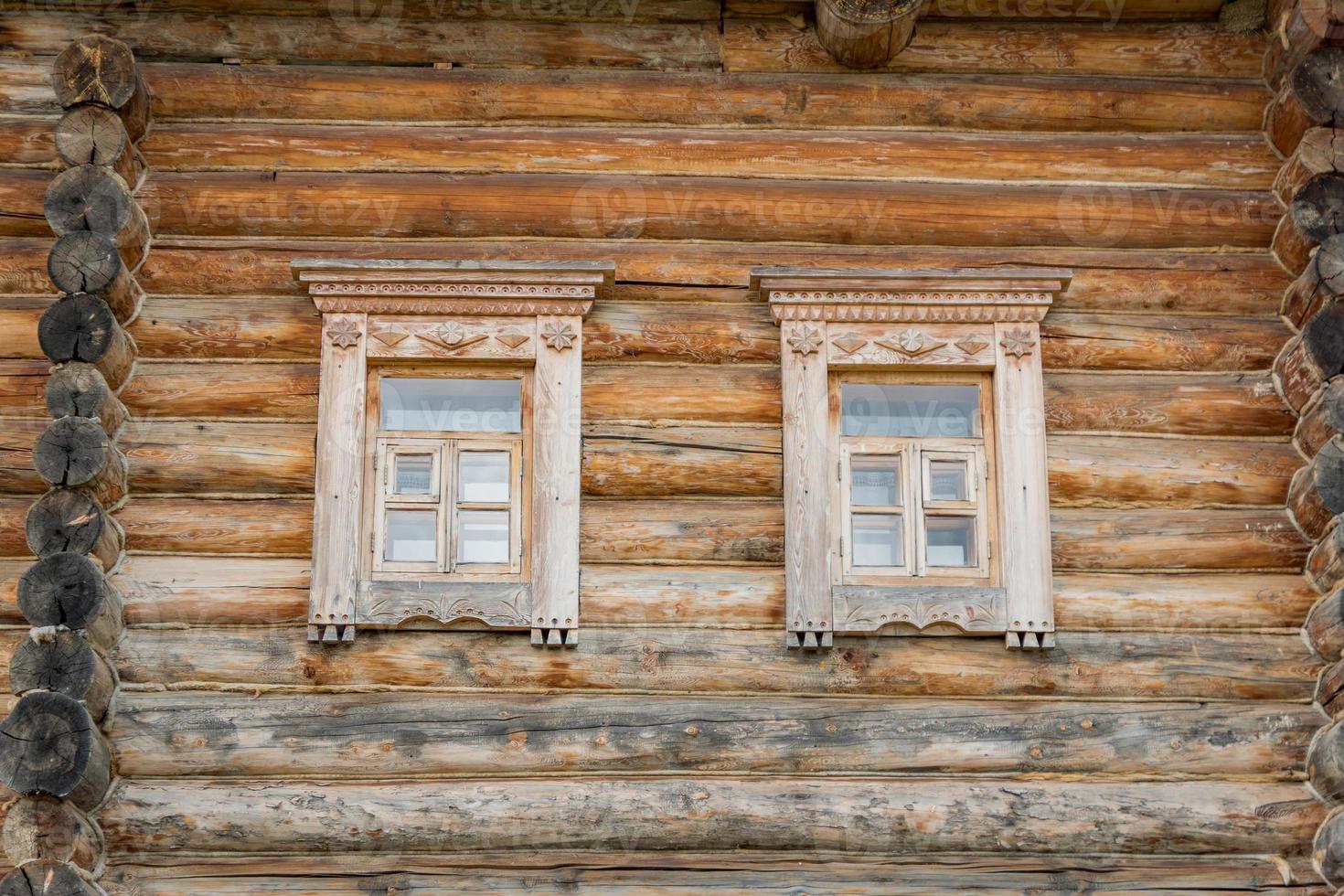 close up of wooden log house. two windows on the wall photo