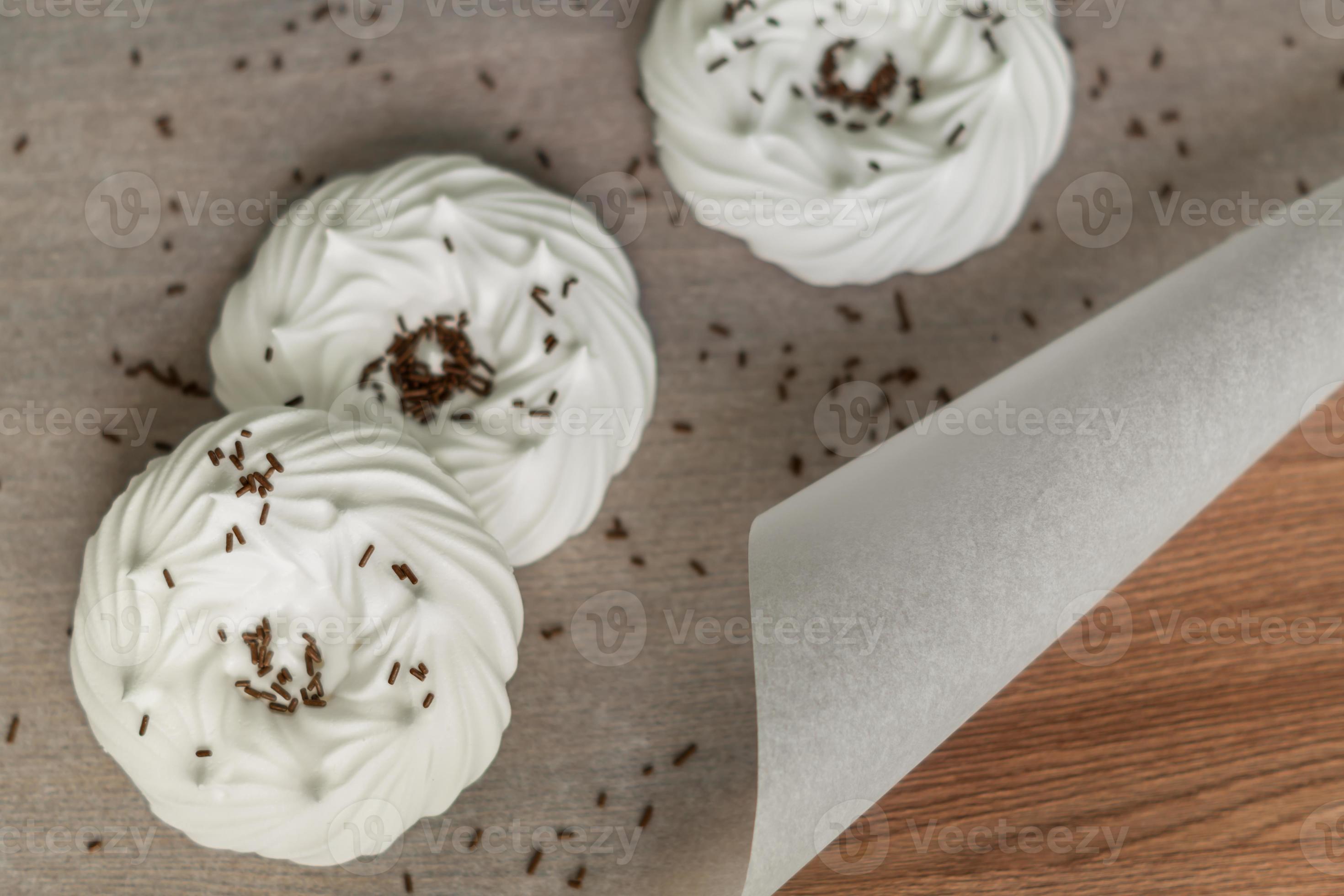 top view of homemade white air meringues and confectionery decorations on on parchment paper