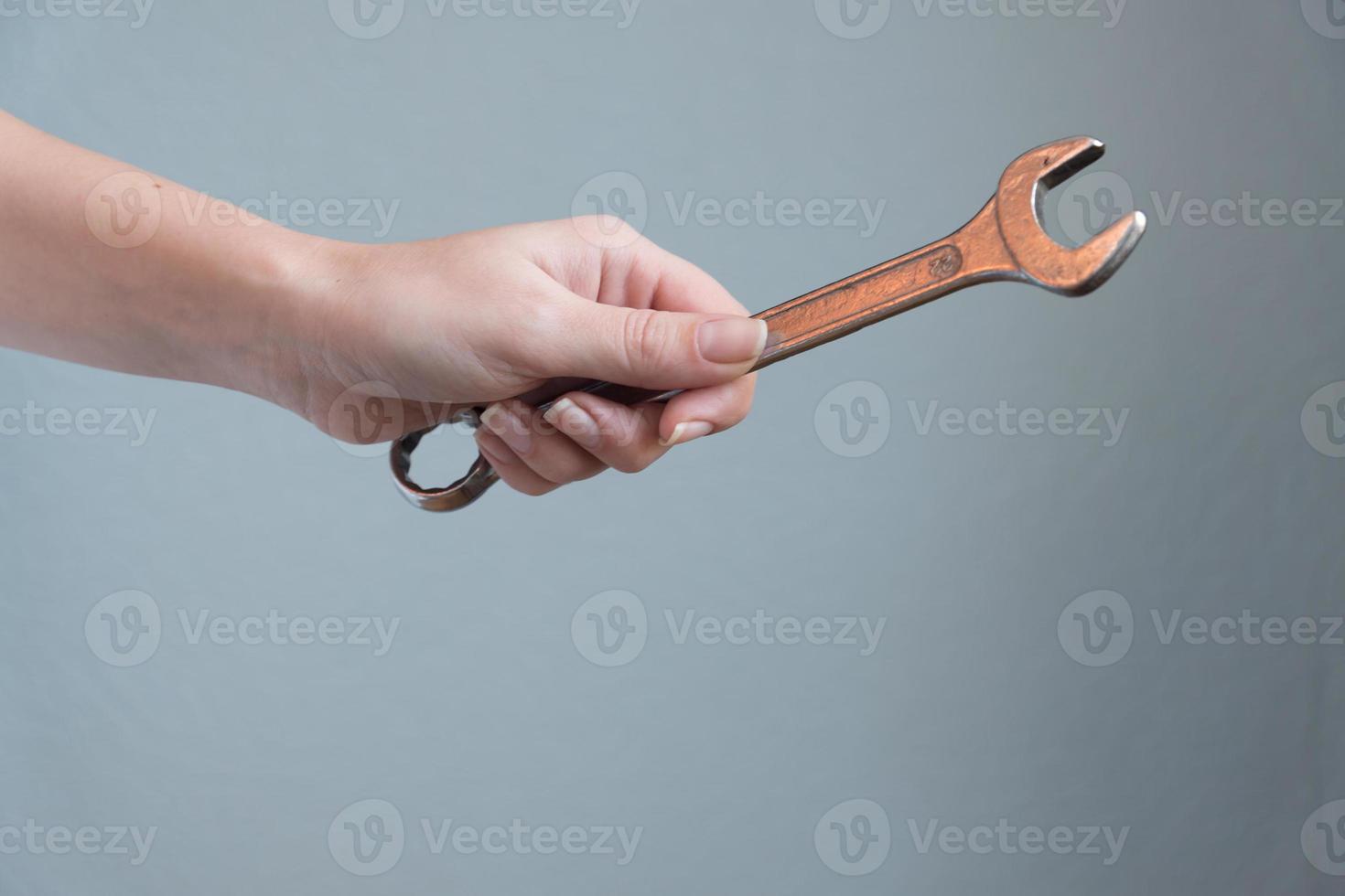 woman holding a wrench in her hand on gray background. photo