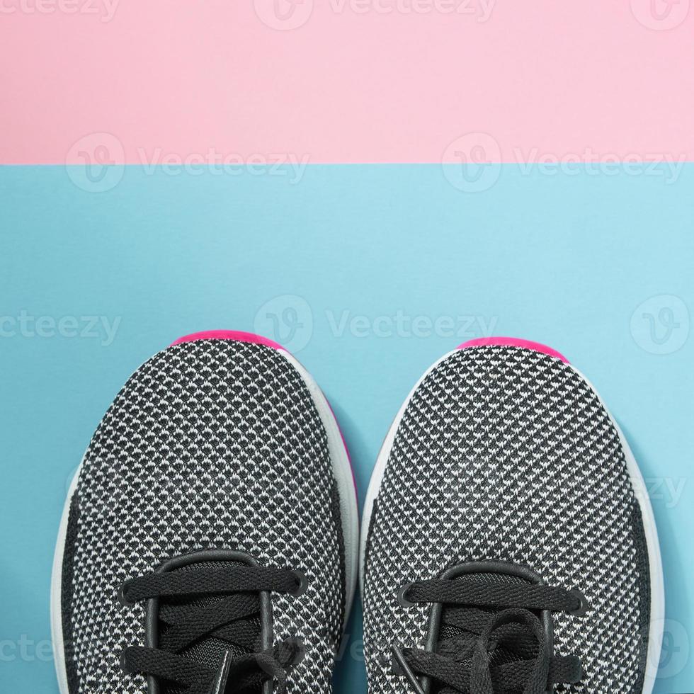 Woman Sneakers lie on a multi-colored pastel pink and blue surface. Top view. photo