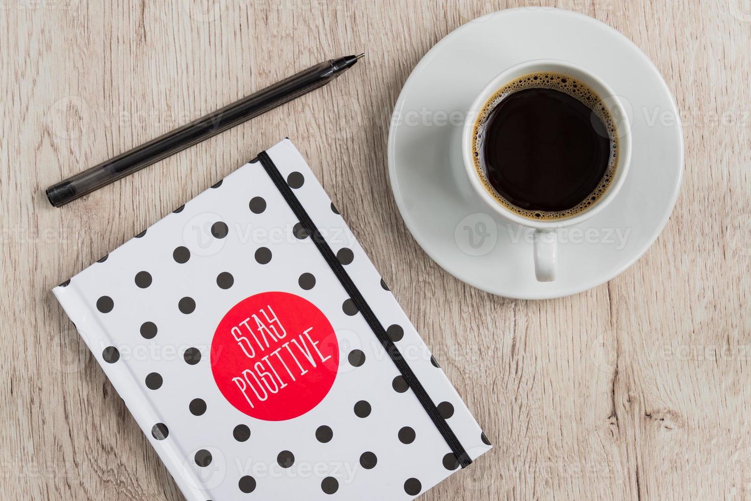 Business and office concept - black and white polka dot cover notebook, smartphone and cup of black coffee on wooden table. top view. photo