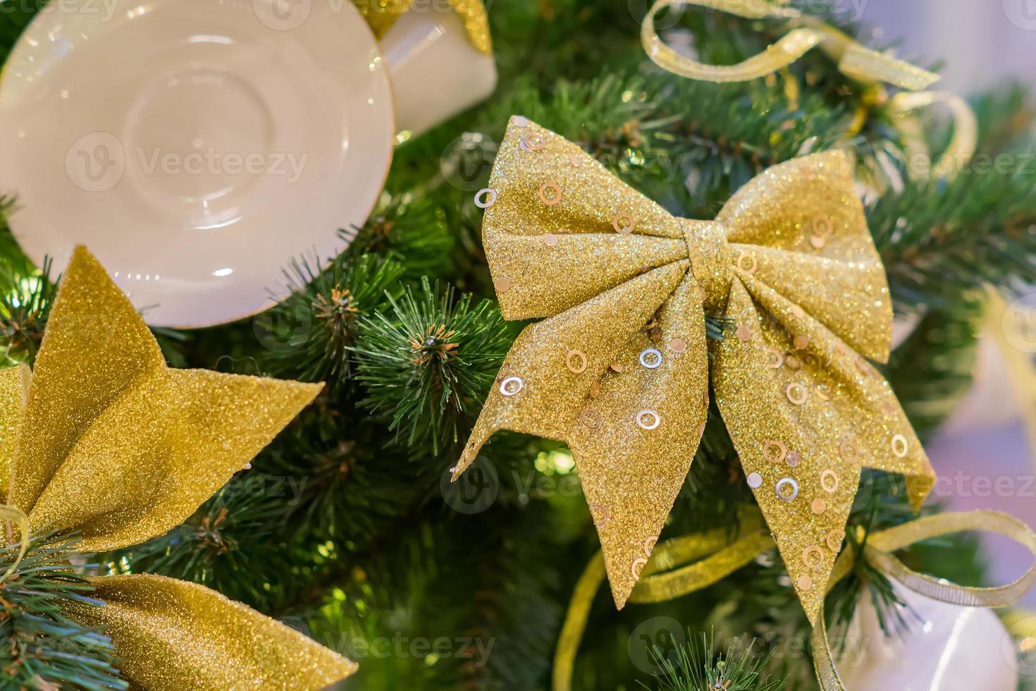 Christmas and New Year holidays background.  Christmas tree decorated with white cups ans sauces and golden bows. Trendy concept photo