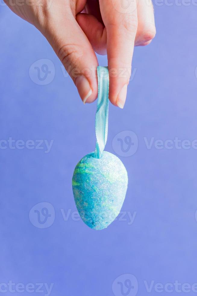 Female hand holding blue sparkling easter egg. photo