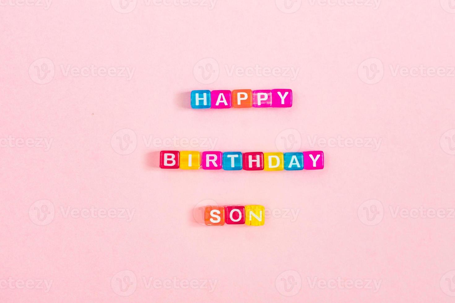 Happy birthday son inscription made of colorful cube beads with letters. Festive pink background concept with copy space photo