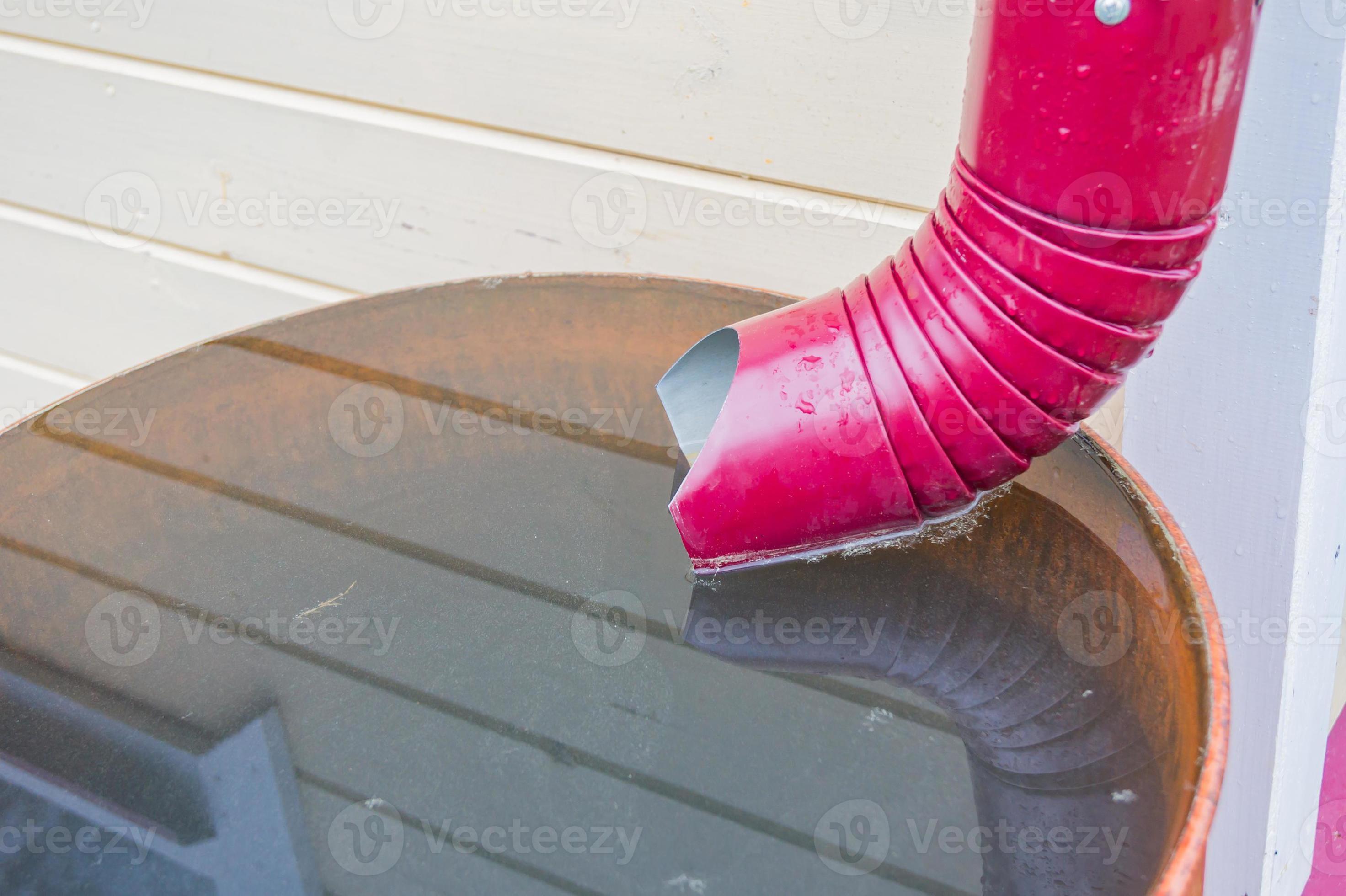 close up of gutter pipe and metal barrel full of water after the rain