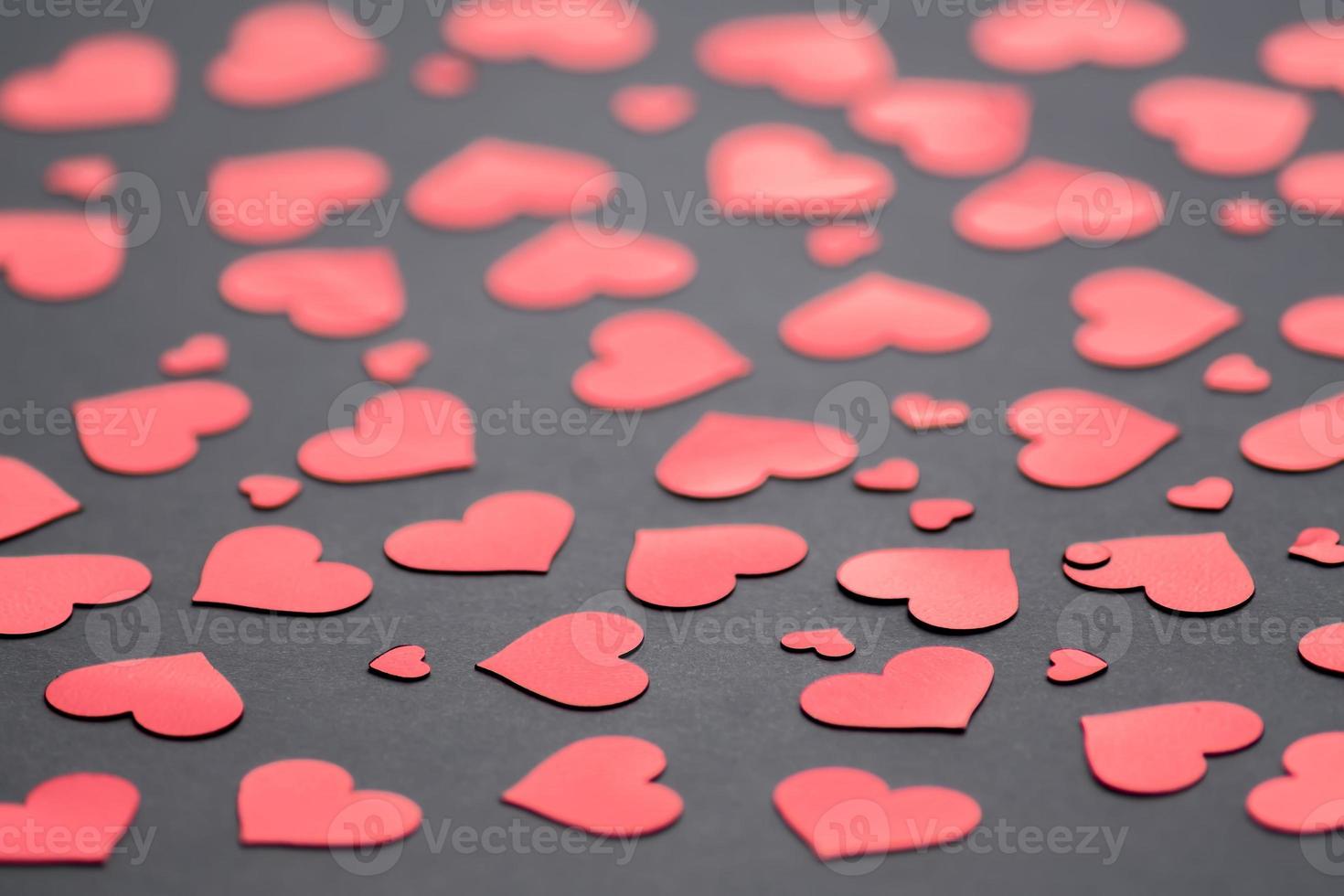 Dark background with red hearts confetti for Valentine's day. Selective focus.  Festive and holiday concept. photo