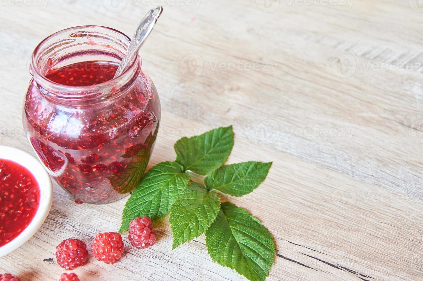 A Jar Of Raspberry Jam On Wooden Table. Copy space for your text photo