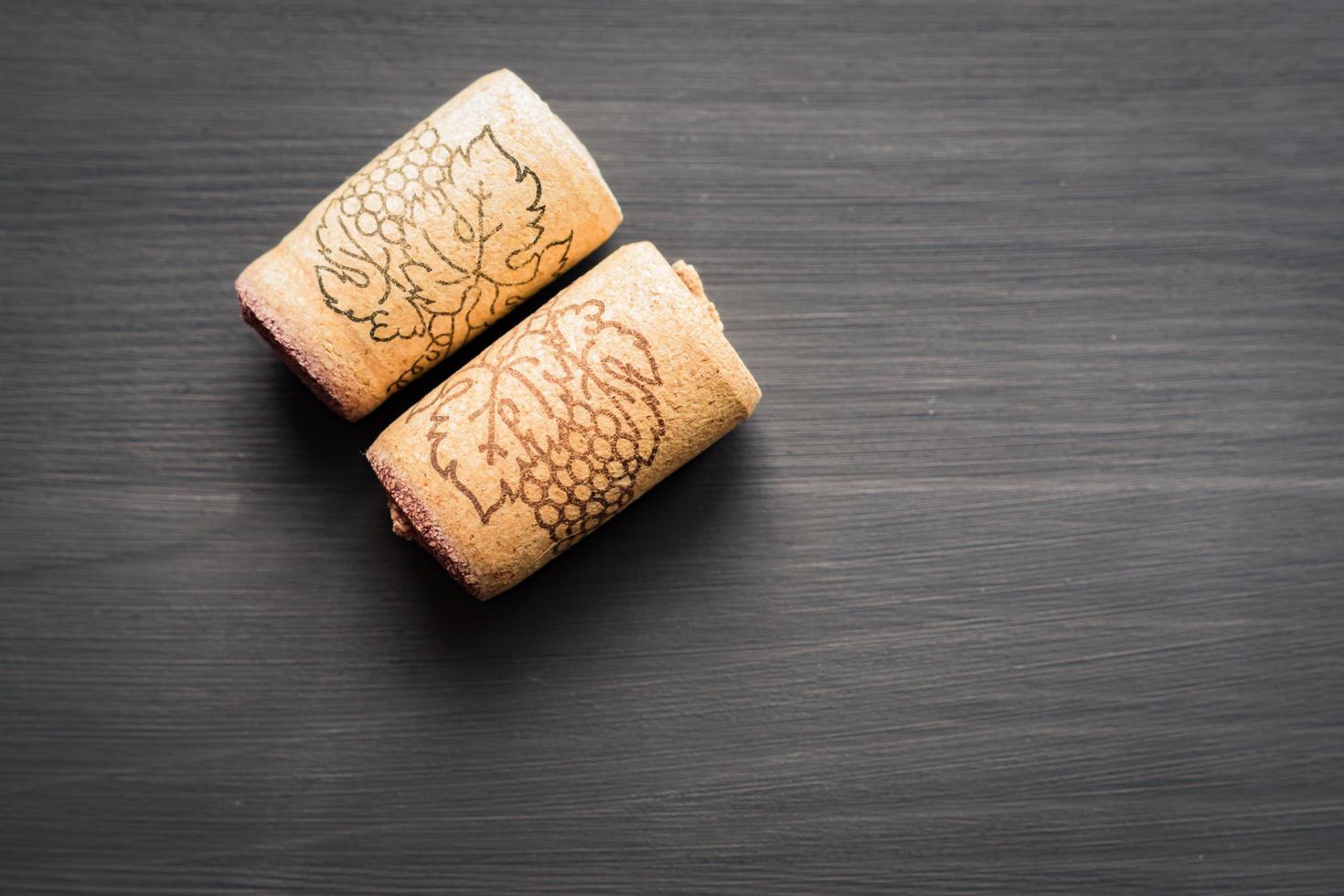 two vine corks on black wooden background with cope space photo