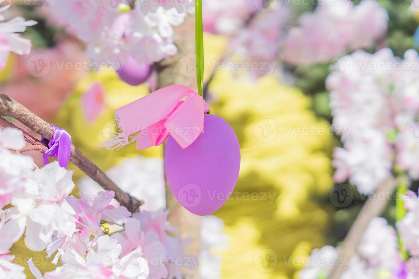 violet easter egg hang on blooming apple tree branch. Easter decoration and celebration concept. photo