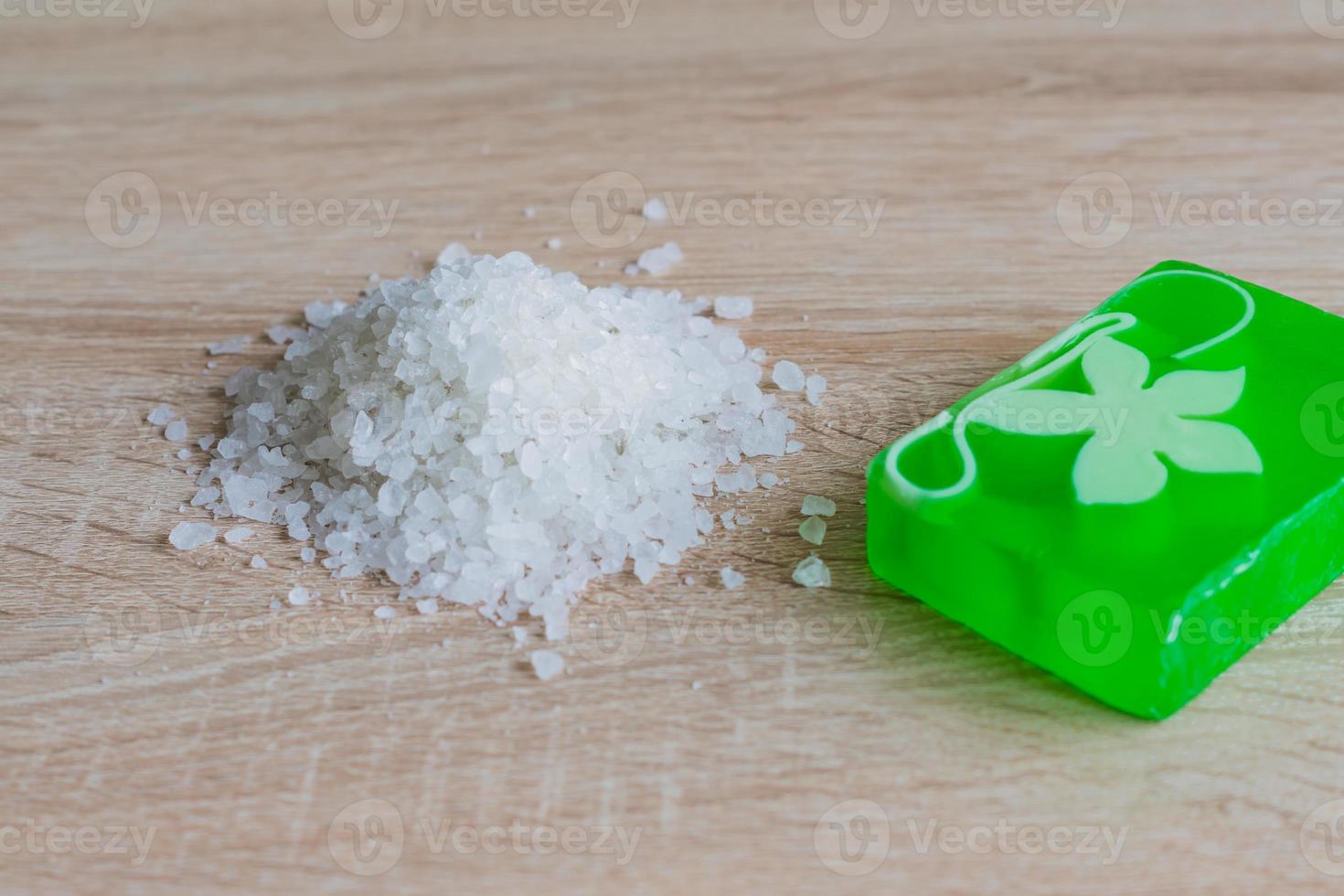 Pile of sea salt and soap bar on wooden table. Natural ingredient for spa and exfoliation. Copy space photo