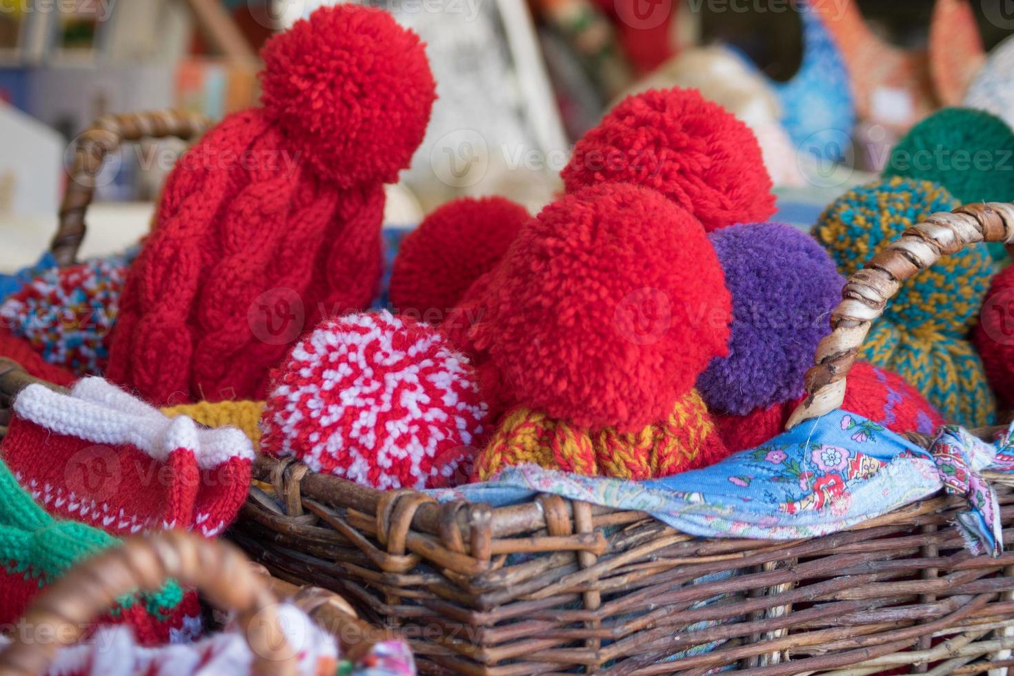 Close up of wicker backet full of knitted wool hats. Christmas fair outdoors. photo