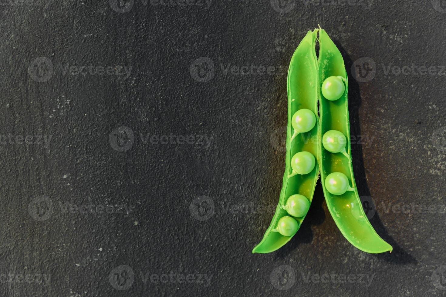 Vegetable backdrop vith copy space for your projects. Close up of fresh ripe green peas on black background photo