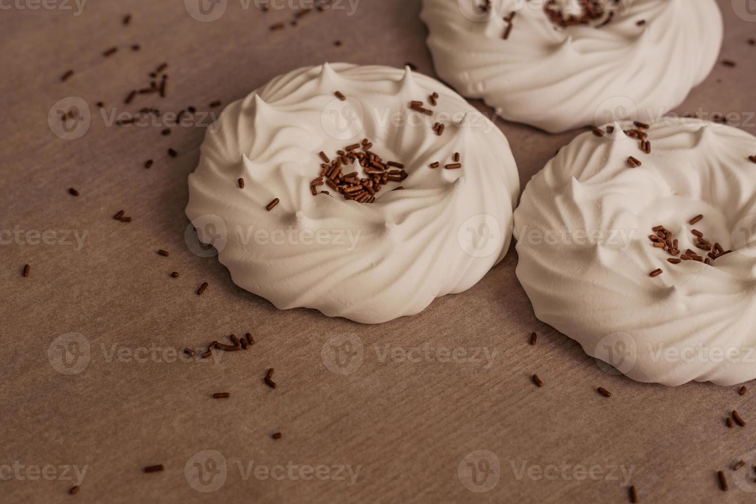 homemade white air meringues and confectionery decorations on  on parchment paper. photo