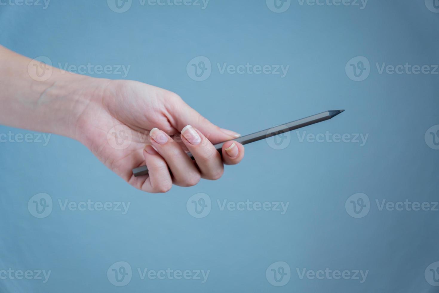 black pencil in woman's hand on blue background. photo