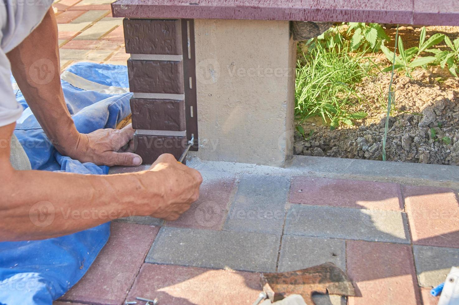 un trabajador instala paneles de revestimiento marrón en la fachada de la casa foto