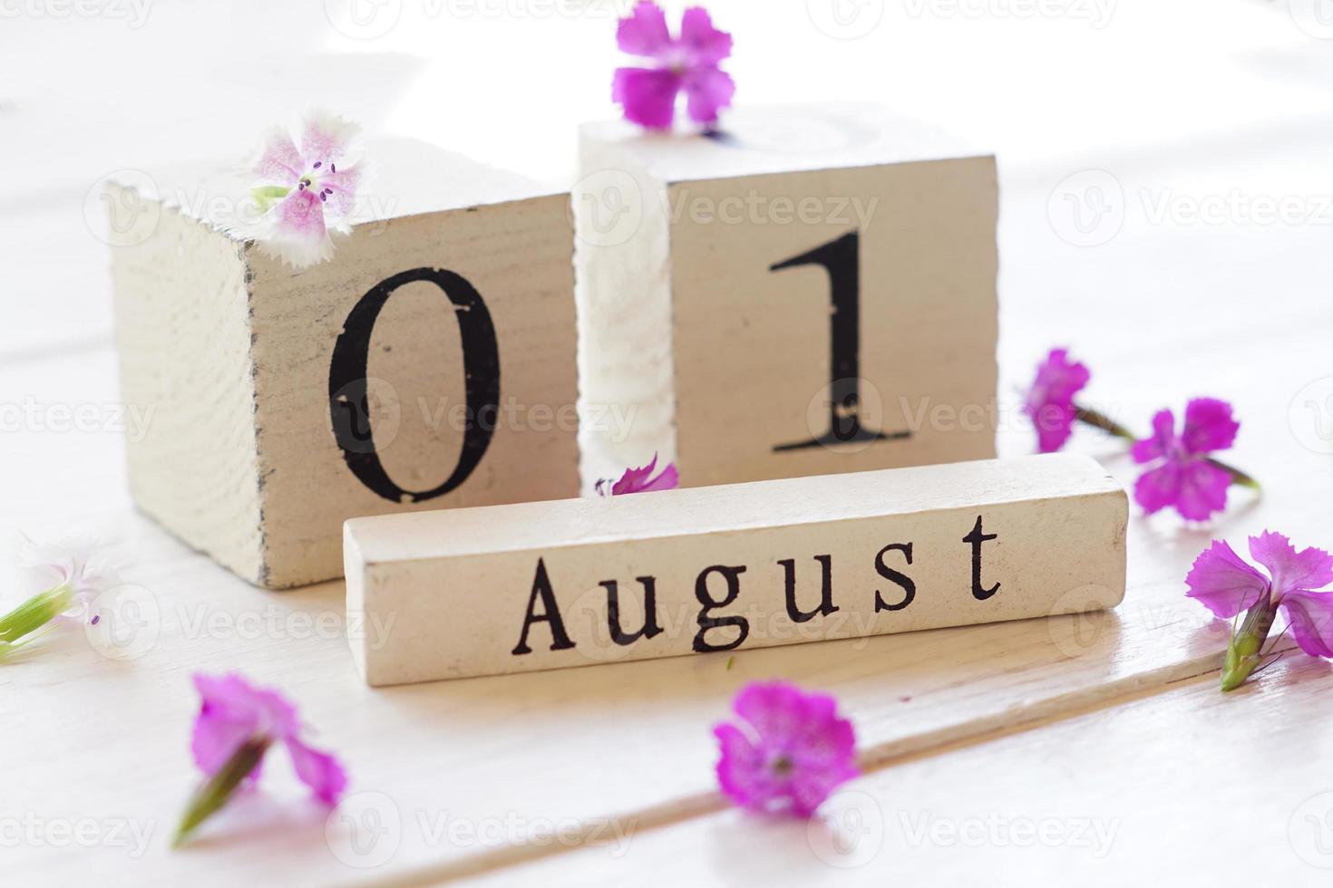 1 August, colorful background with cube wooden calendar and pink flowers photo