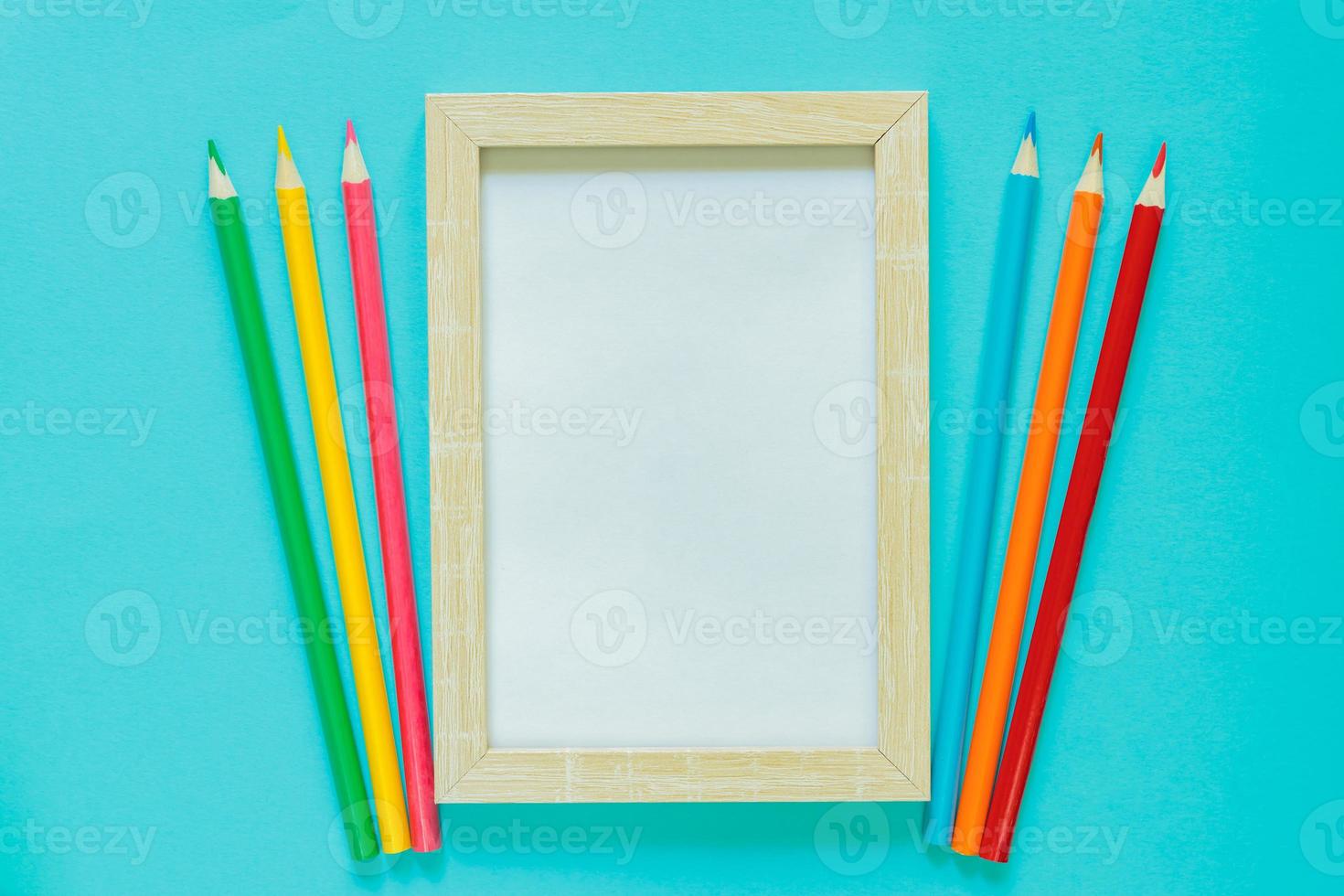 Creative flat lay with school suppllies. Mock up frame and multicolored pencils on blue background. Back to school. photo