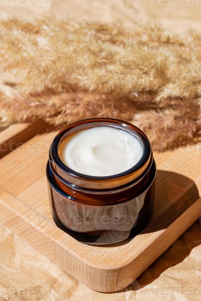 Open jar with face cream on a wooden tray. Cosmetic container mock-up. Background for branding and packaging presentation. Natural skincare beauty product concept. photo